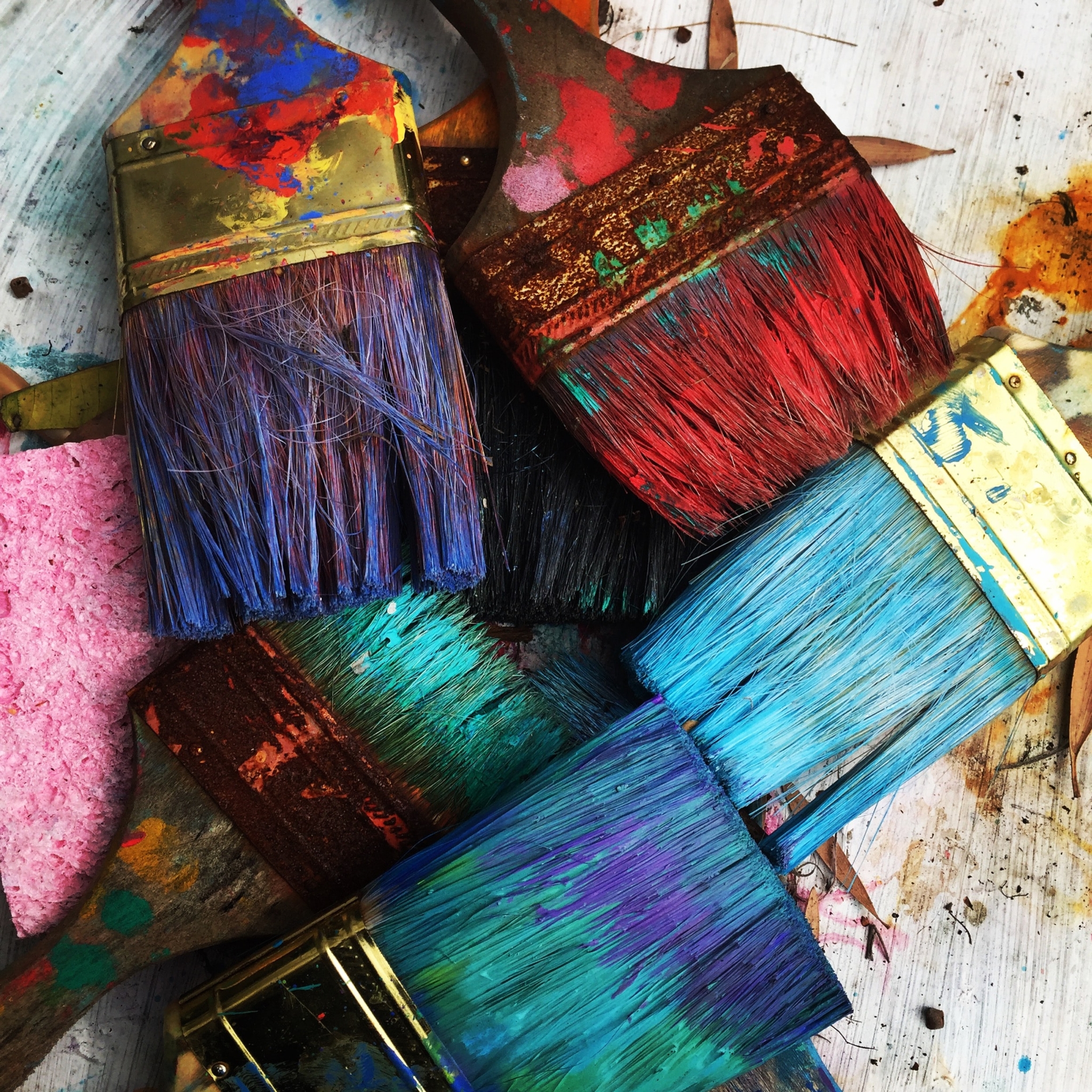 Broad paint brushes with various colors on them.