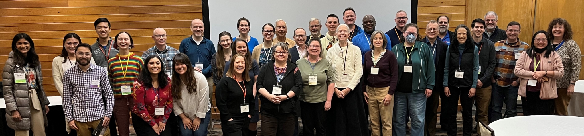 A large group of people with name tags smile for the camera.